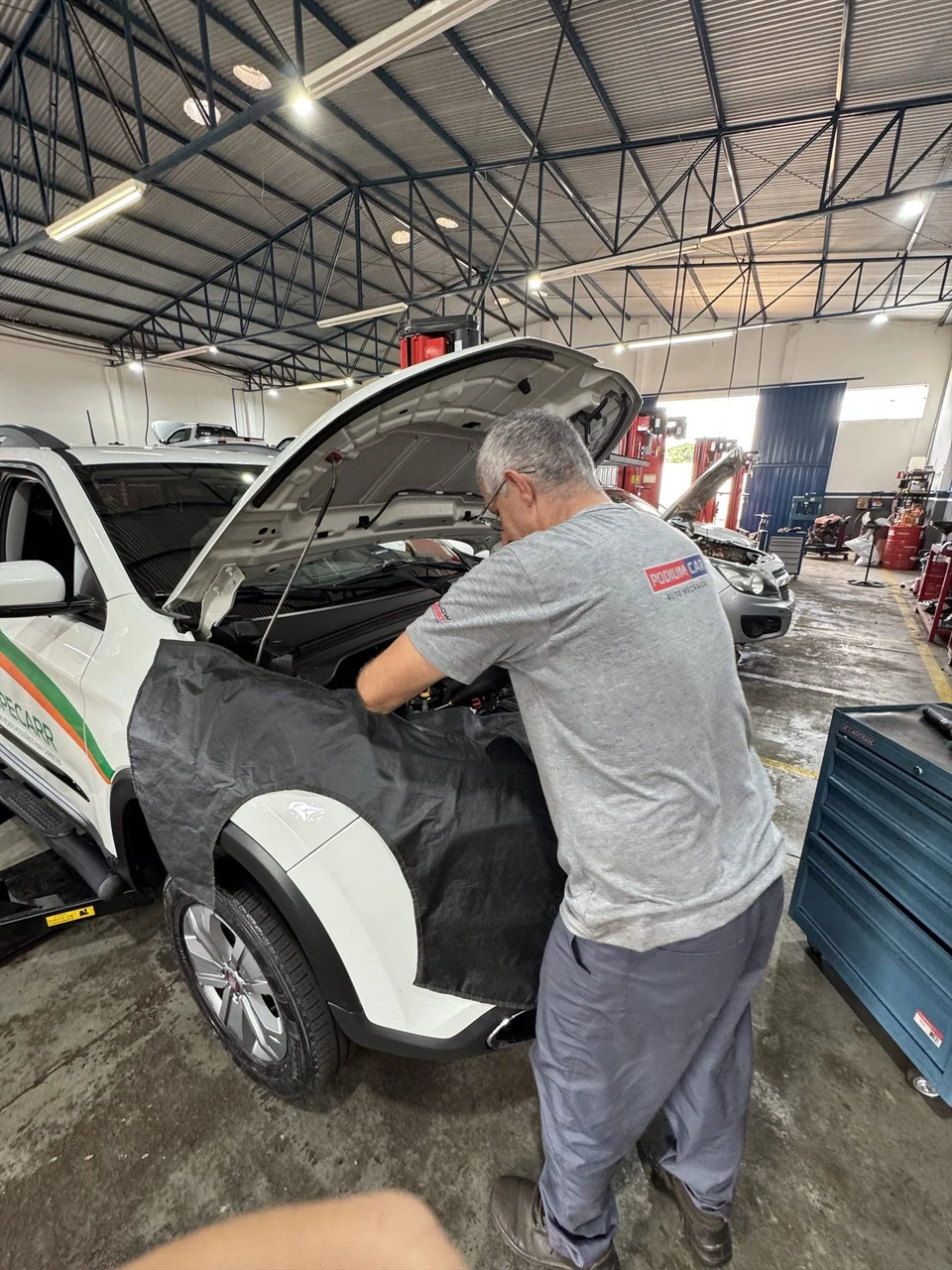 Mecânico realizando uma revisão em veículo na Podium Car
